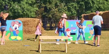 Children playing outdoors near hay bales and colorful decorations.