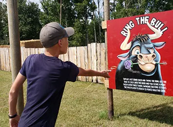 A man playfully hits a donkey piñata at an outdoor event.